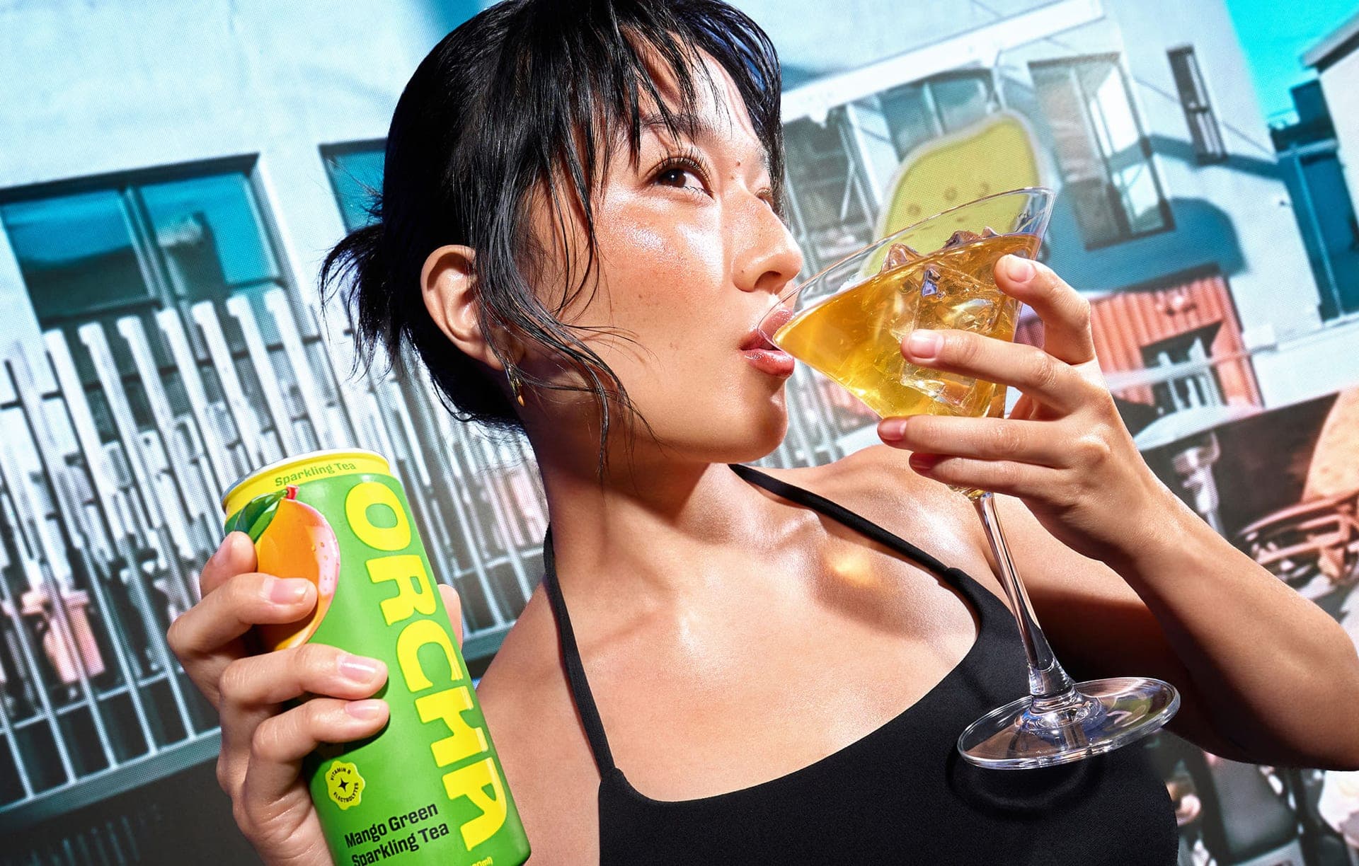 A person sipping Orcha sparkling tea over ice while holding an Orcha can outdoors.